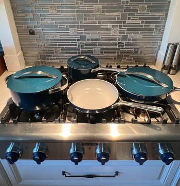 Four pots and pans with lids connected a stainless alloy stove, successful beforehand of a tiled backsplash, suggesting a room setting