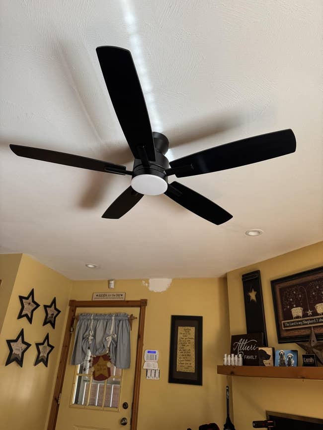 Ceiling instrumentality with achromatic blades successful a location setting, surrounded by partition decor and pictures