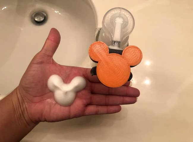person with foaming hand soap in the shape of mickey mouse on their hand