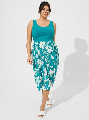 model in scoop neck sleeveless teal midi dress with solid bodice and white flowers on the skirt