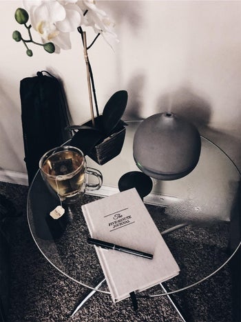 Reviewer image of product on top of a clear table with a pen on top of it next to a mug of tea, flower, and diffuser