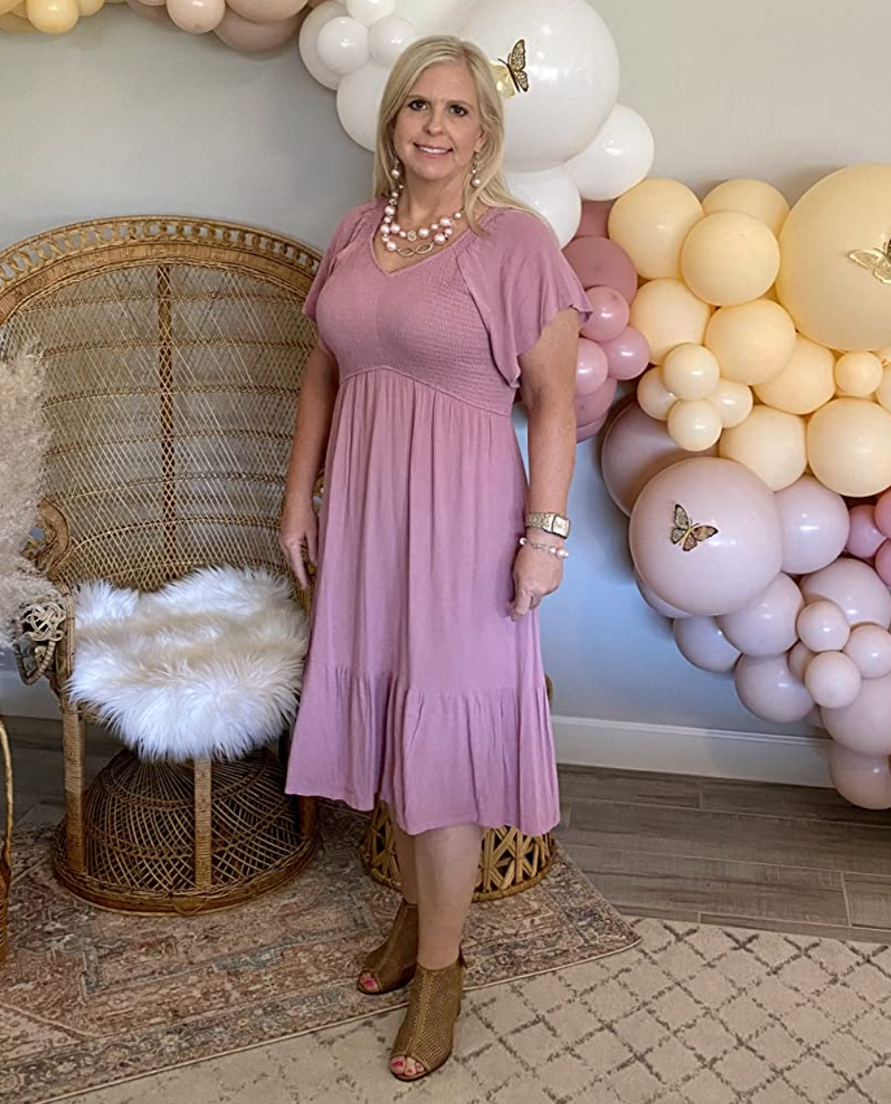 Reviewer in a pink v-neck tiered midi dress with fluttery sleeves 