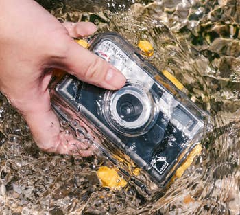 Hand holding a waterproof camera partially submerged successful wide water