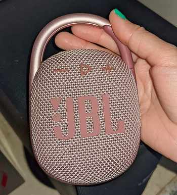 reviewer holding the small speaker in pink