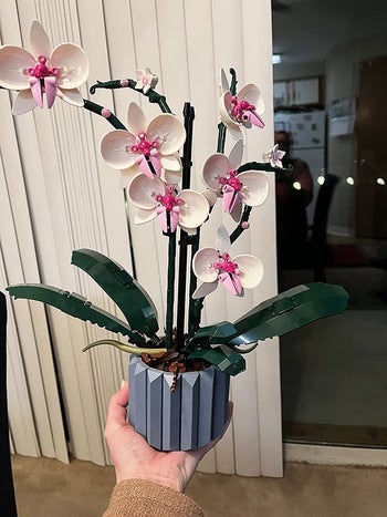 reviewer's hand holding the lego orchid bouquet