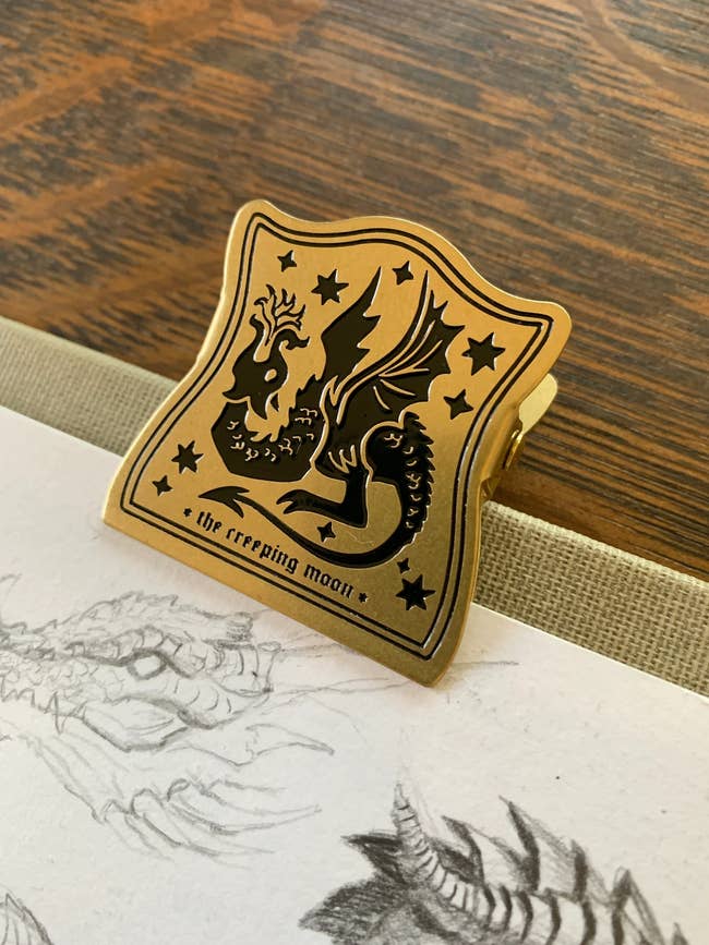 A metallic clip with a dragon emblem and stars