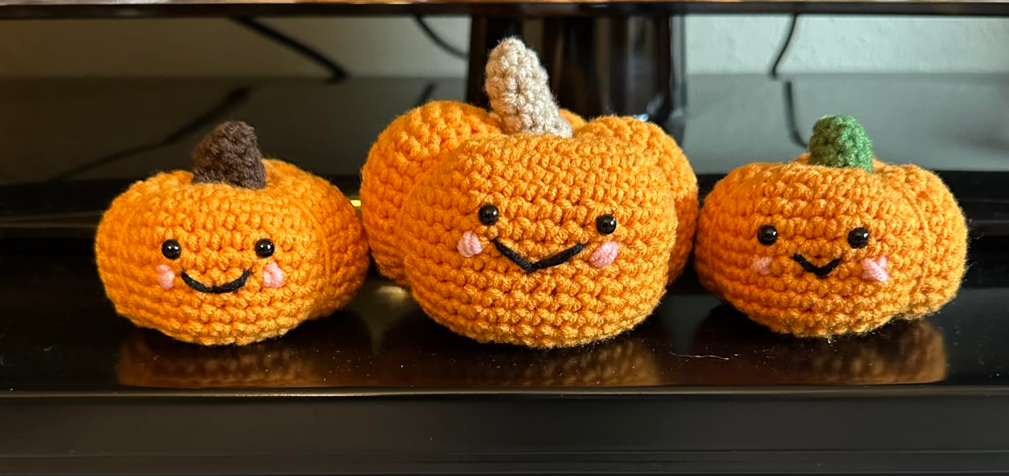 Three crochet pumpkins with smiling faces