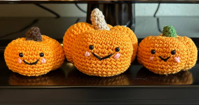 Three crochet pumpkins with smiling faces