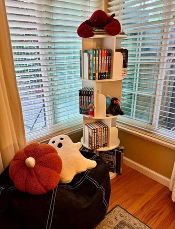Cozy country   with a circular  bookshelf featuring assorted  books, a pumpkin and shade  pillow connected  a achromatic  legume  bag, and stuffed toys