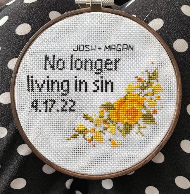 cross stitch with two names and a date with a floral detail. it says no longer living in sin.