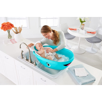 A model giving baby a bath in the whale tub