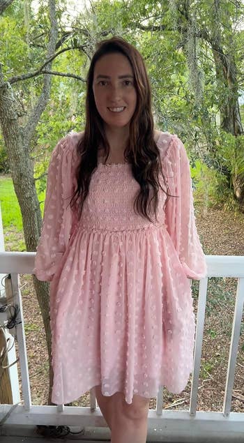reviewer in a pink dress with polka dot details standing on a porch