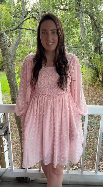 reviewer in a pink dress with polka dot details standing on a porch