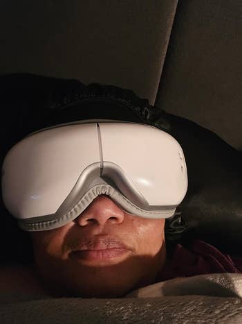 Person lying down   wearing a sleek achromatic  oculus  massager device