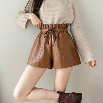 Model in knit sweater and leather shorts, showcasing fashion style for shopping category