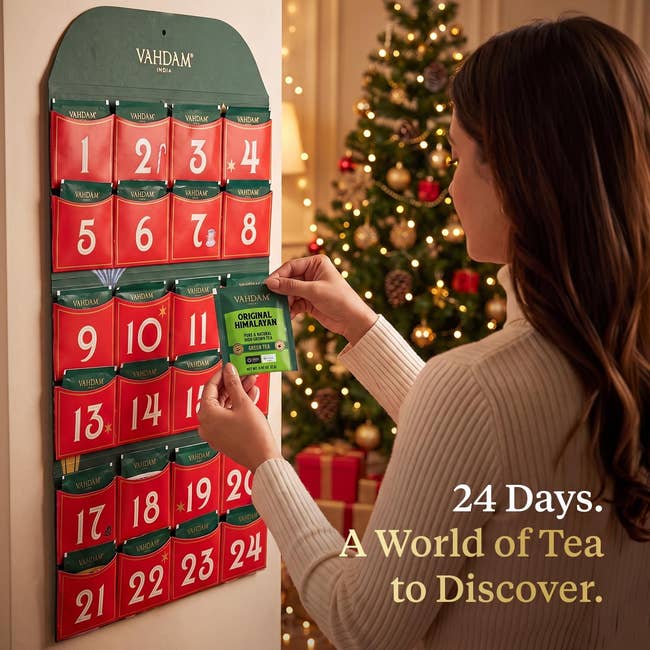 Person utilizing a beverage advent calendar with numbered pockets, successful beforehand of a decorated Christmas tree, accompanied by the substance