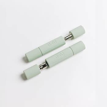 Two pastel silicone dumbbells with metallic connectors, designed for compact at-home workouts