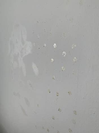 reviewer image of a wall before with lots of small adhesive dots on it