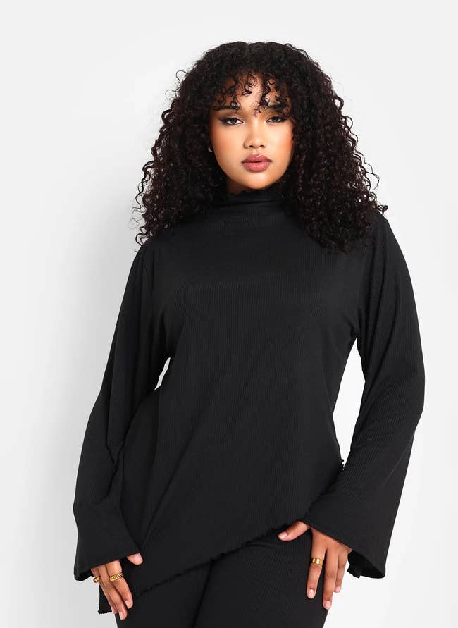 Woman in a stylish black turtleneck with an asymmetrical design, suitable for shopping category content