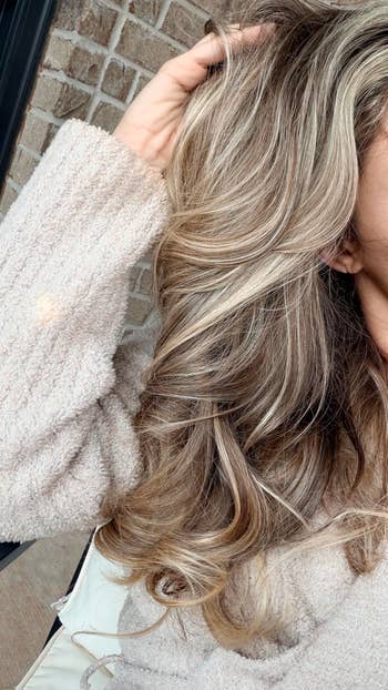 Person wearing a cozy textured sweater, showcasing voluminous and styled wavy hair