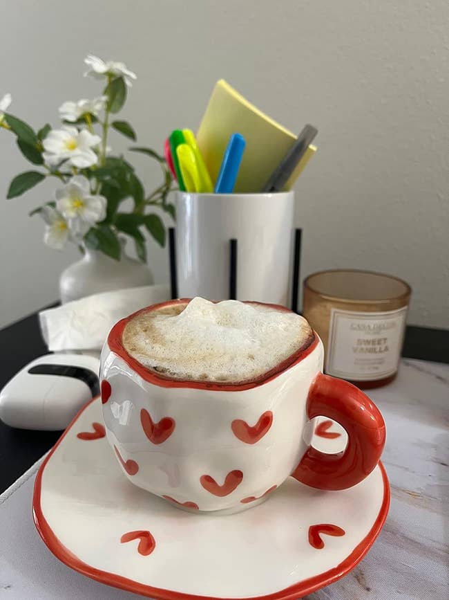a white mug with tiny hearts on it and a matching saucer