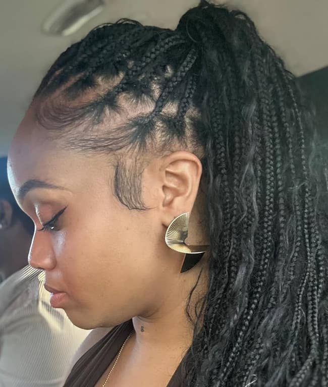 Close-up side profile of a reviewer with braided hair and large, geometric earrings