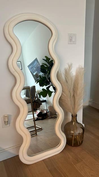 the white wavy mirror leaning against a wall