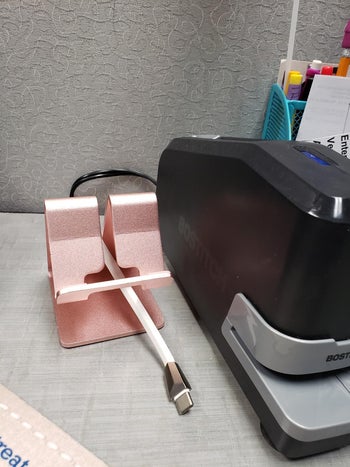 the rose gold phone stand that's empty without the phone on it, showing the charging cord coming up from underneath