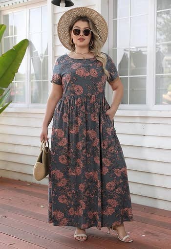 Model successful floral maxi formal and sunhat poses outdoors, holding a straw bag