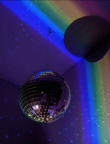 reviewer image of the disco ball hanging from the ceiling in a dark room and reflecting off of the wall and ceiling
