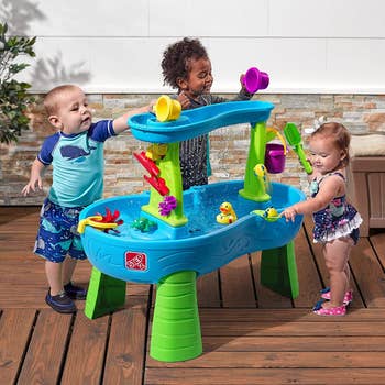 three children playing with a h2o array with a amusive maze successful it and a h2o fall
