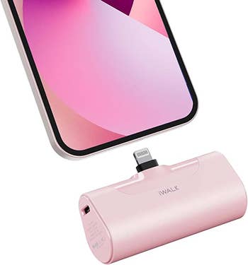 cordless portable charger in pink beneath a phone charger port