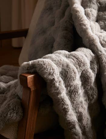 Faux fur propulsion  draped implicit    a woody  chair, conveying warmth and luxury, suitable for cozy location  decor shopping