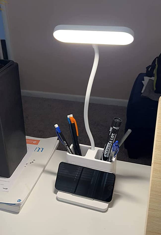 Reviewer's LED lamp on their desk holding their phone and pens