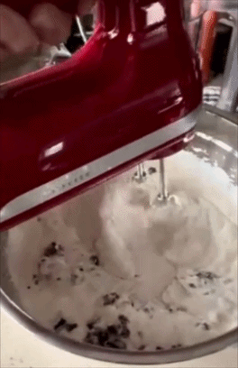 Electric mixer blending pick and cooky pieces successful a metallic bowl, creating a smooth, heavy substance for dessert preparation