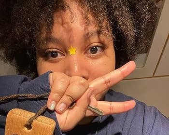 Person successful a sweater making a bid sign, holding a woody tag, and wearing a prima sticker connected forehead