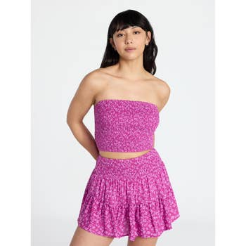 Woman modeling a strapless tube top with a matching floral skirt set, posing with hands behind her back