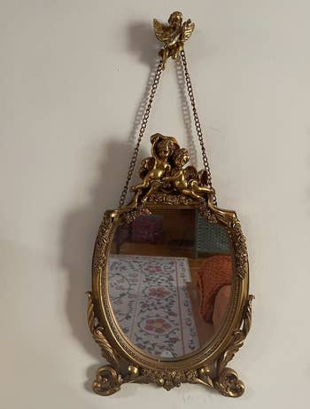 Ornate vintage mirror with angel and lion detail, reflecting a room's interior