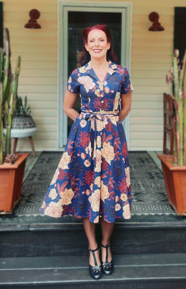 Person successful  a vintage floral formal  stands connected  a porch, surrounded by potted plants, exuding a classical  and elegant style