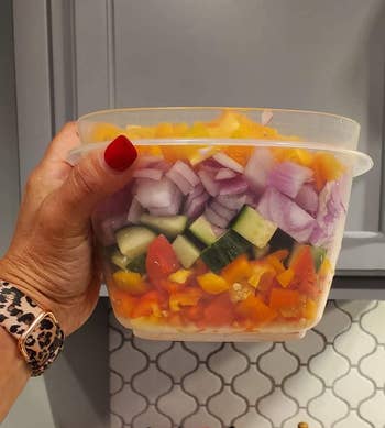 reviewer holding a container of assorted chopped vegetables