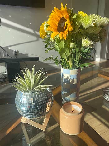 the disco ball planter on a coffee table next to flowers and candle
