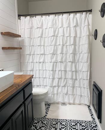 reviewer photo of the white ruffled shower curtain in their bathroom