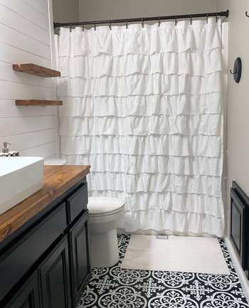 reviewer photo of the white ruffled shower curtain in their bathroom