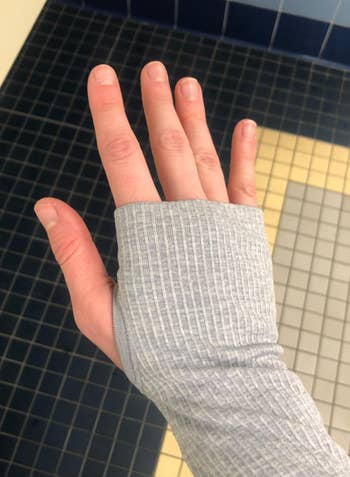 Reviewer showing sleeve of gray version with their thumb in the hole 