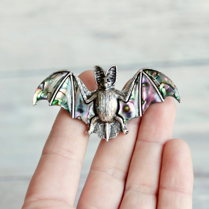 hand holding a bat shaped drawer pull with pearl inlay on wings