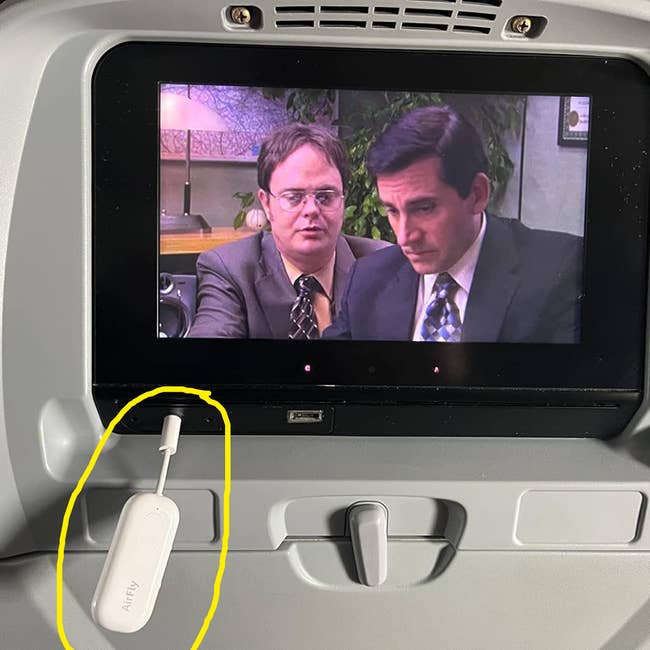 Airplane movie screen shown with AirFly plug in to connect wireless headphones to movie