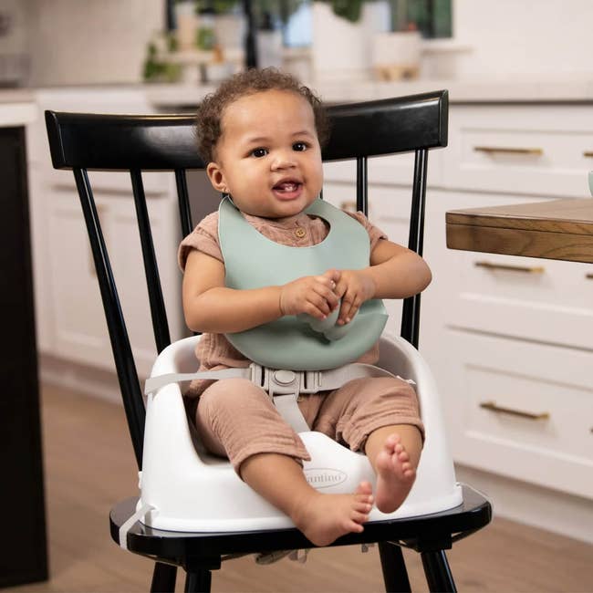 Baby seated connected  a precocious   seat  with a silicone bib, sitting successful  a modern   room  setting