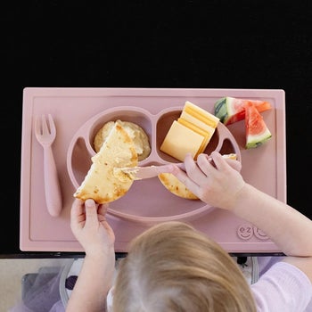 kid sitting using happy mat with food in compartments