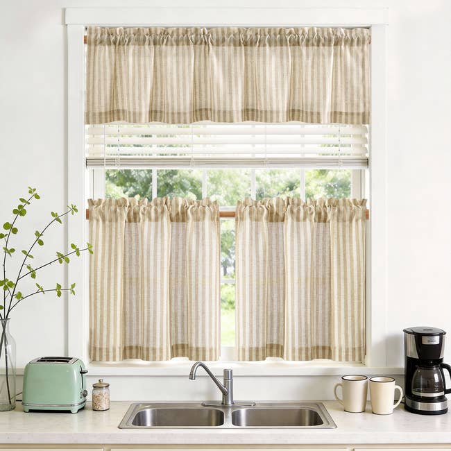 Kitchen model   with striped curtains, a descend  below, a toaster, java  maker, and 2  mugs connected  the counter