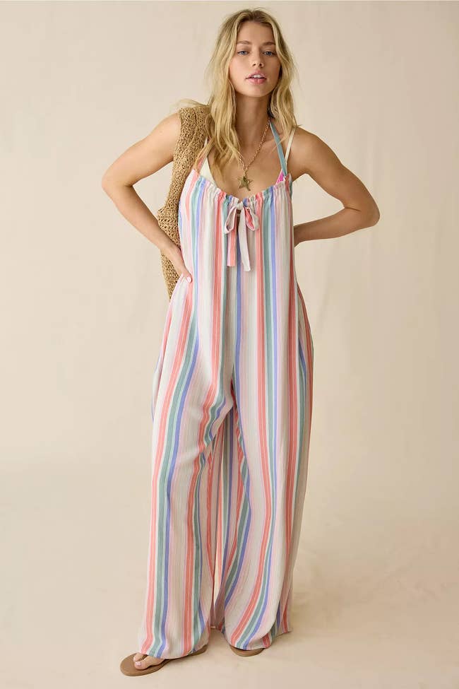 Model successful  striped, loose-fitting jumpsuit holding a woven bag, suitable for a casual, stylish look